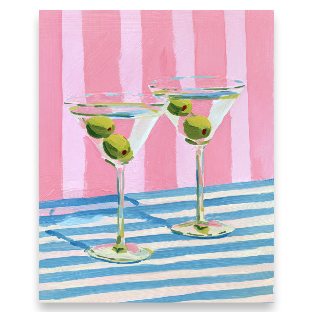 Two martini glasses with olives on a pink and blue striped background